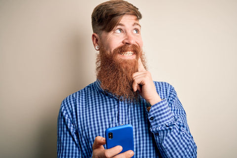 man with beard holding phone