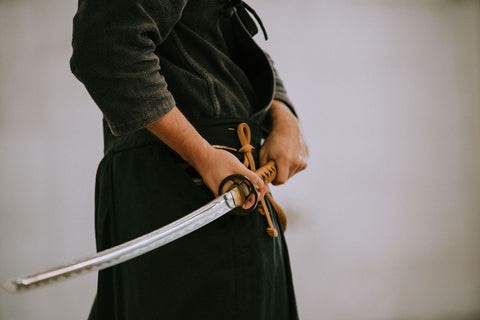 Man in black worn gi with a katana at rest