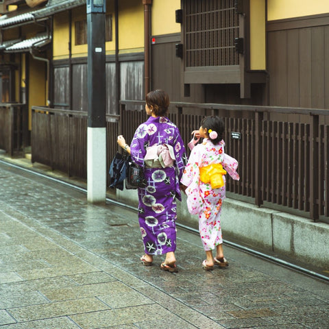 Mother and daughter wearing ceremonial kimonos walking down a village street.