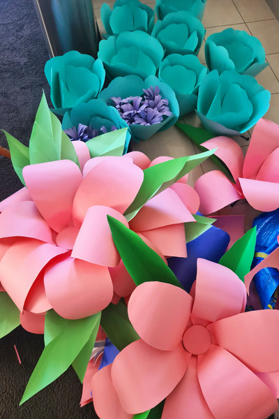 A collection of giant paper flowers, including daisies, ready to be installed