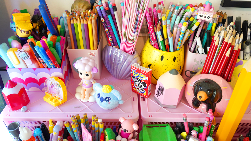 A colourful collection of kawaii stationery, arranged in various colourful cups and containers