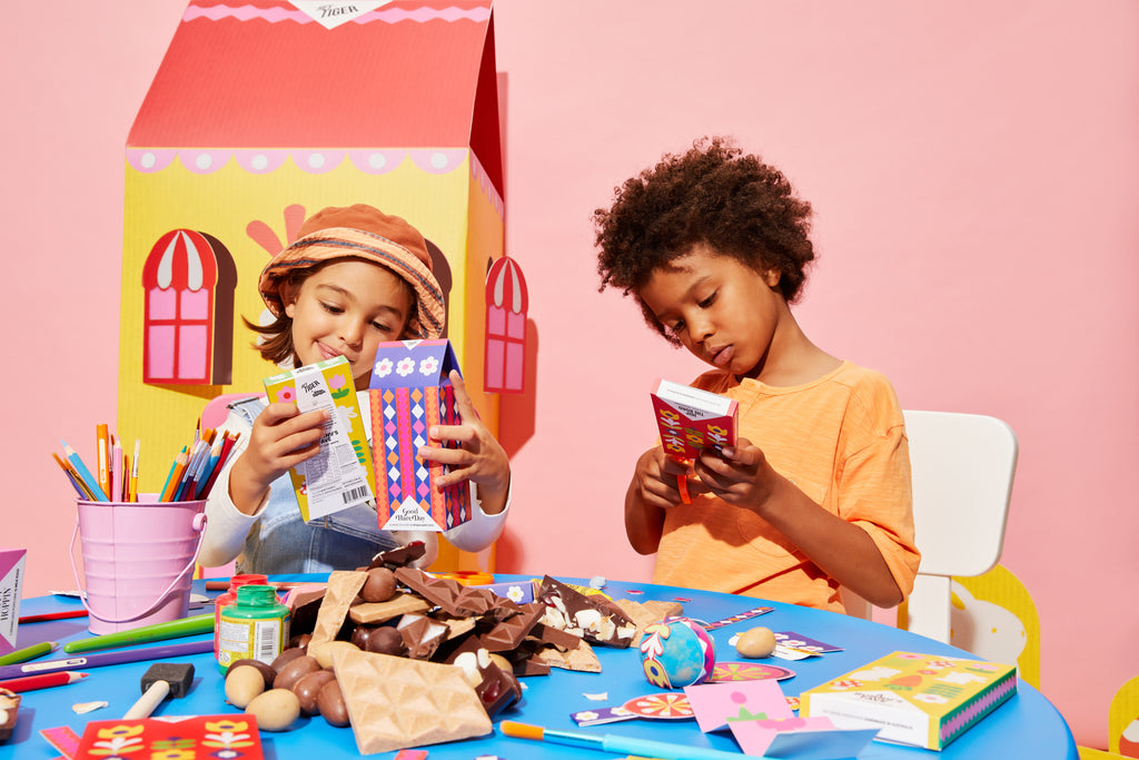 Kitiya Palaskas's collaboration with Hey Tiger Chocolate, with packaging design made using papercraft illustrations. In this image, children enjoy the chocolate and are surrounded by lifesize paper props
