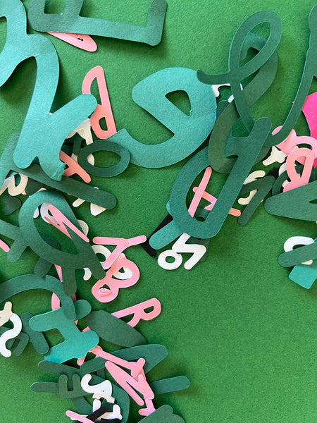 A close up photo of colourful letters cut out out paper.
