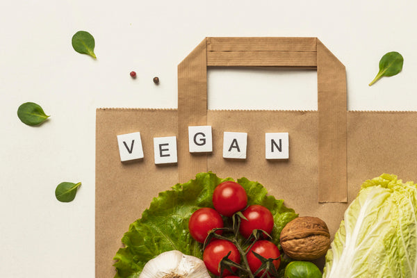 a image of organic fruits and vegetables on a paper bag with the word "vegan" spelled out on the bag.