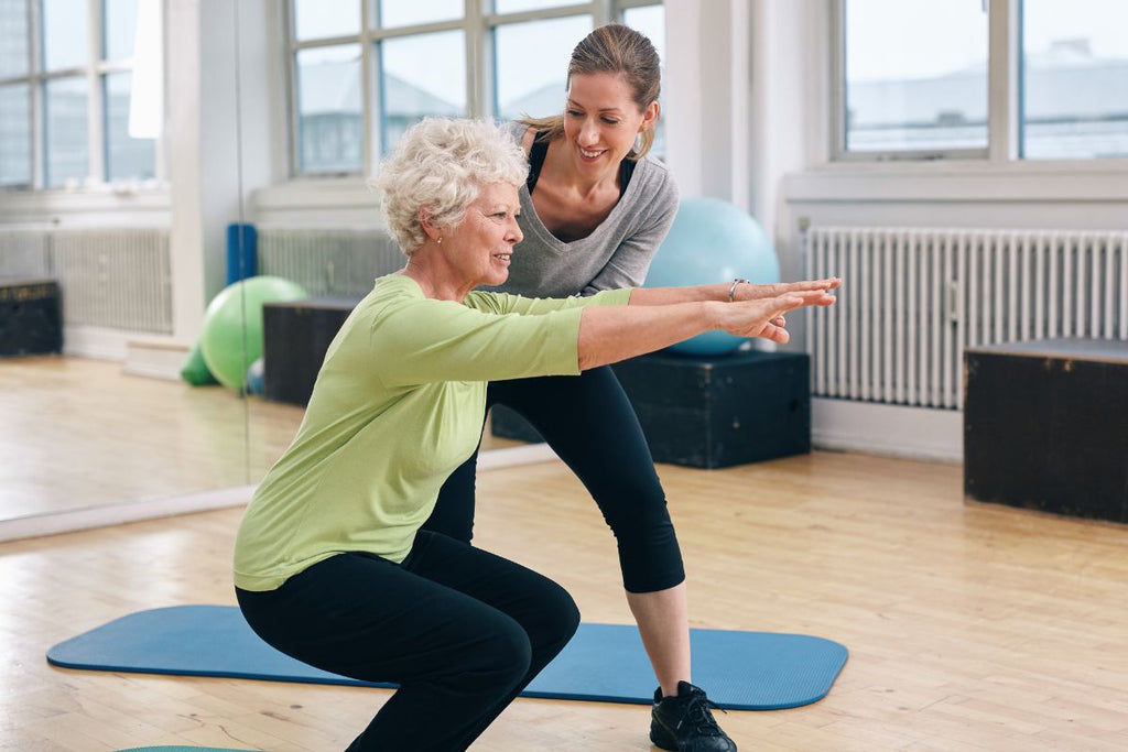Uma pessoa de mais idade com uma personal trainer realizando atividade física.