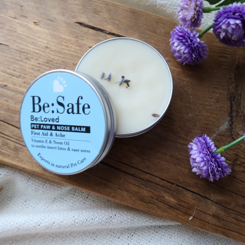 Be:Safe Balm product and tin label on wooden shelf with flowers on it too