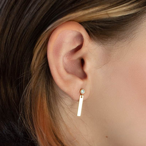A woman wears CZ stud earring with a bar charm