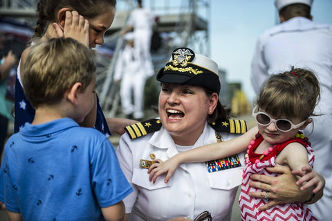 Female sailor in dress uniform hugging children