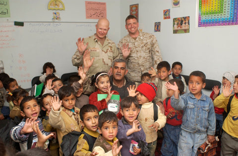 Army Soldier David Flynn posing in classroom with Iraqi children