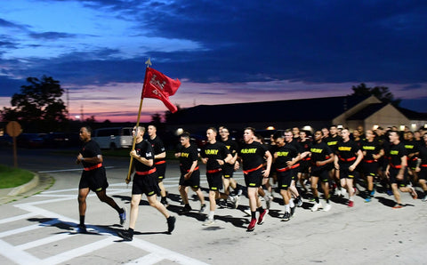 Army soldiers in black PT gear running in formation