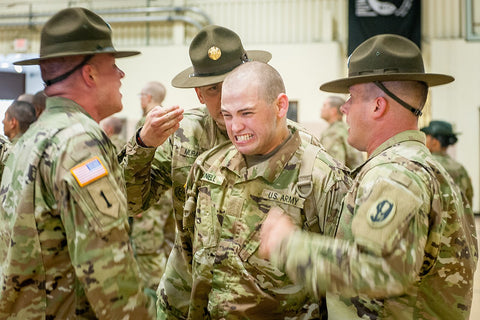 three army drill instructors yelling at a recruit