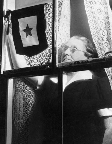 Antique photo of woman putting blue star flag in window