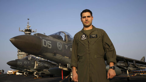 Male pilot in flight suit on a carrier in front of jet.