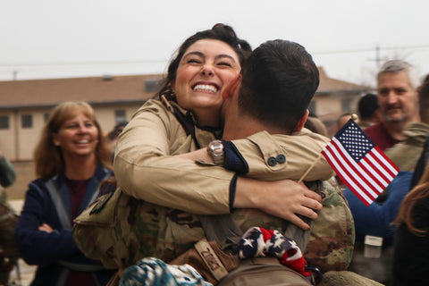 Soldier hugging wife with crowd in background