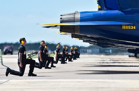 Airmen kneeling behind Blue Angels jets