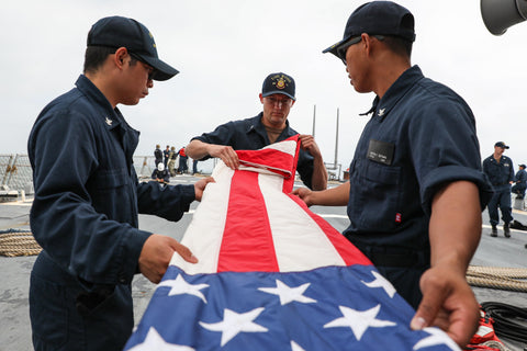 US Navy sailors folding American flag