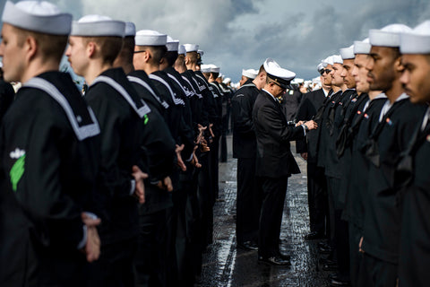 USN sailors in dress uniform being inspected by an officer