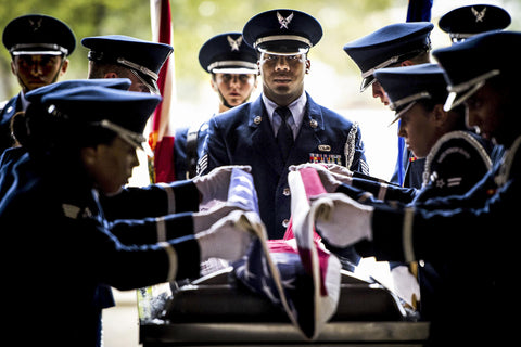 Air Force Personnel in dress uniforms folding American flag over casket 