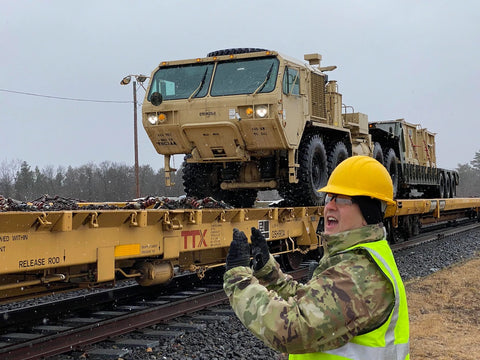 Army Reservist by railroad car with army truck on it