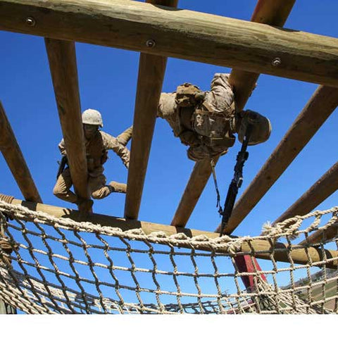 marines climbing over a cargo net obstacle