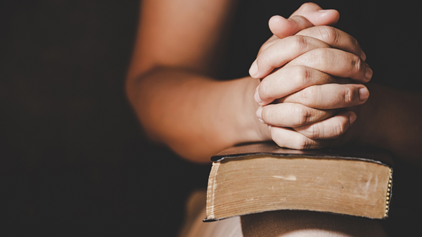 Prayer hands on Bible