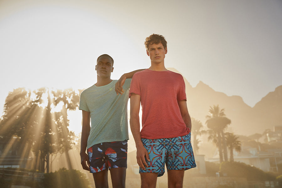 Two men stood on the beach with linen t-shirts on