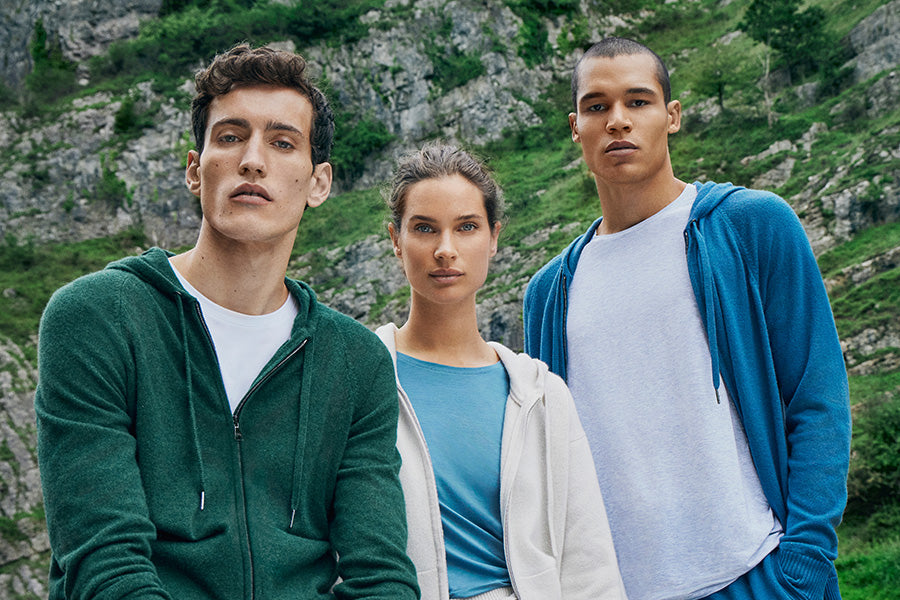 Two men and a woman outisde wearing matching cashmere hoodies