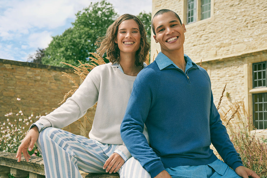 Man and woman sat on a wall in matching pyjamas and cashmere jumpers