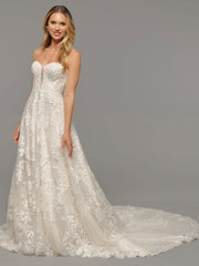 Image of blonde woman modeling a lace wedding dress with a train.