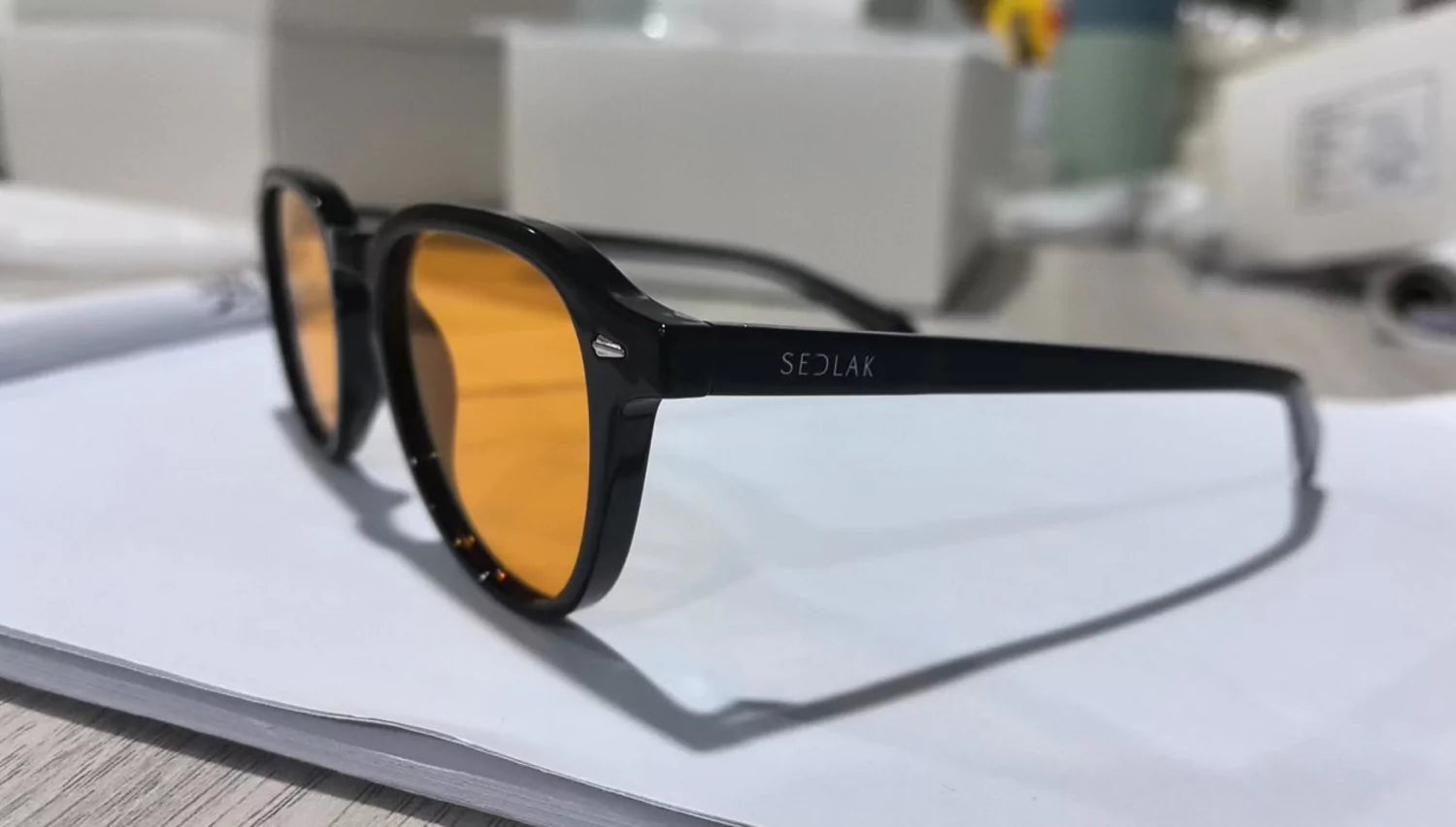 Pair of black-framed sunglasses with amber lenses on a white surface.