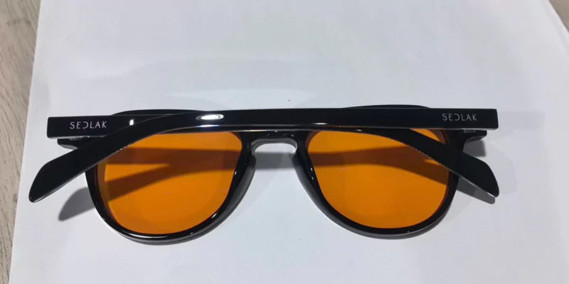 Black sunglasses with orange lenses on a white surface.