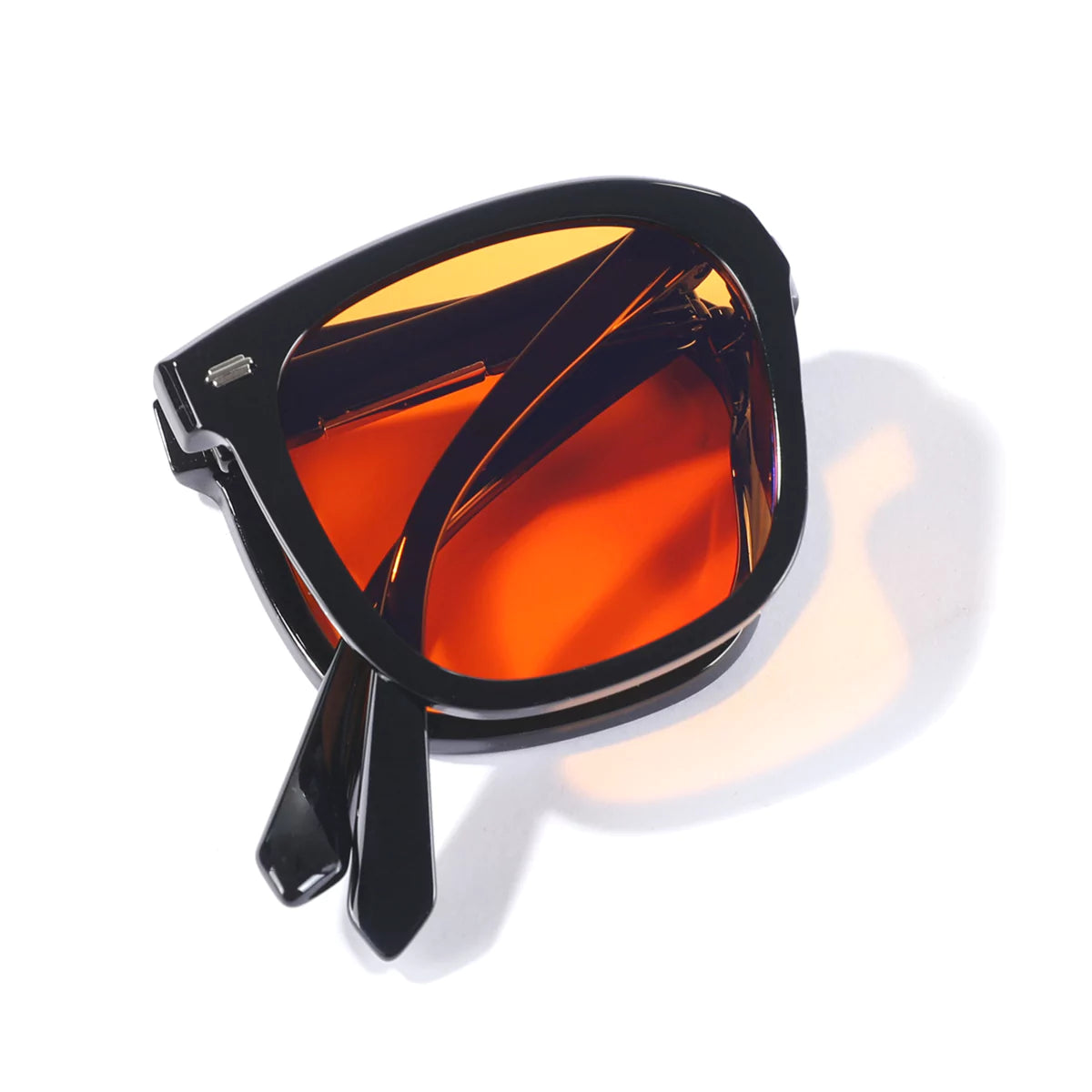 A pair of black-framed sunglasses with orange lenses on a white background.