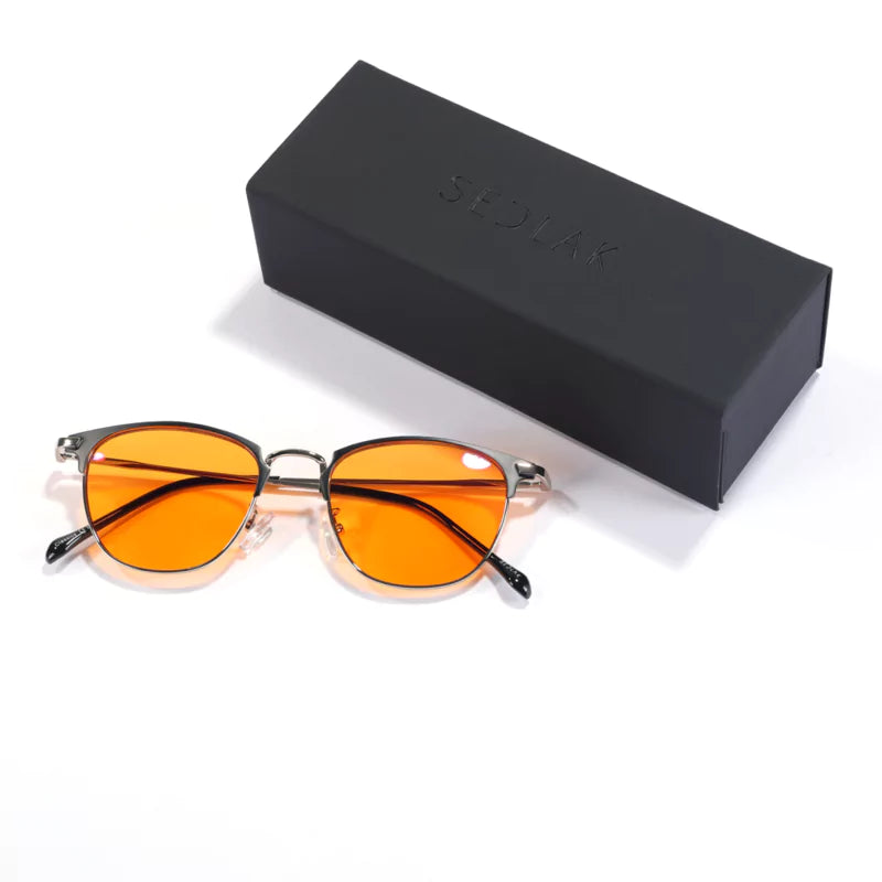 Orange-lens sunglasses next to a black glasses case with the brand name embossed.