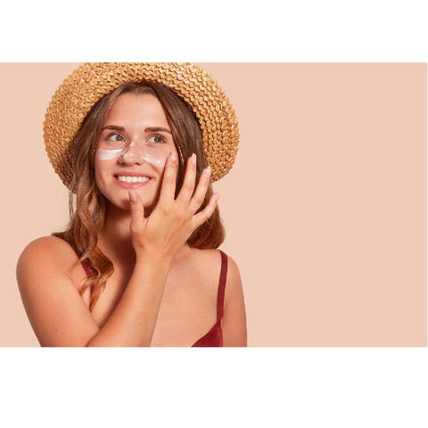 jeune femme souriante en chapeau de paille protège la peau de son visage avec une crème solaire