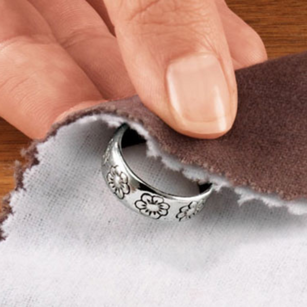 person polishing silver ring with cloth