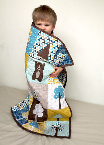 Boy wrapped in "Our Forest Winter" quilt