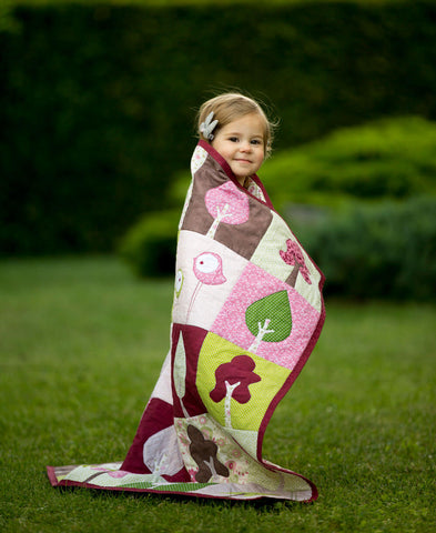 Girl wrapped in "Our Forest Spring" quilt