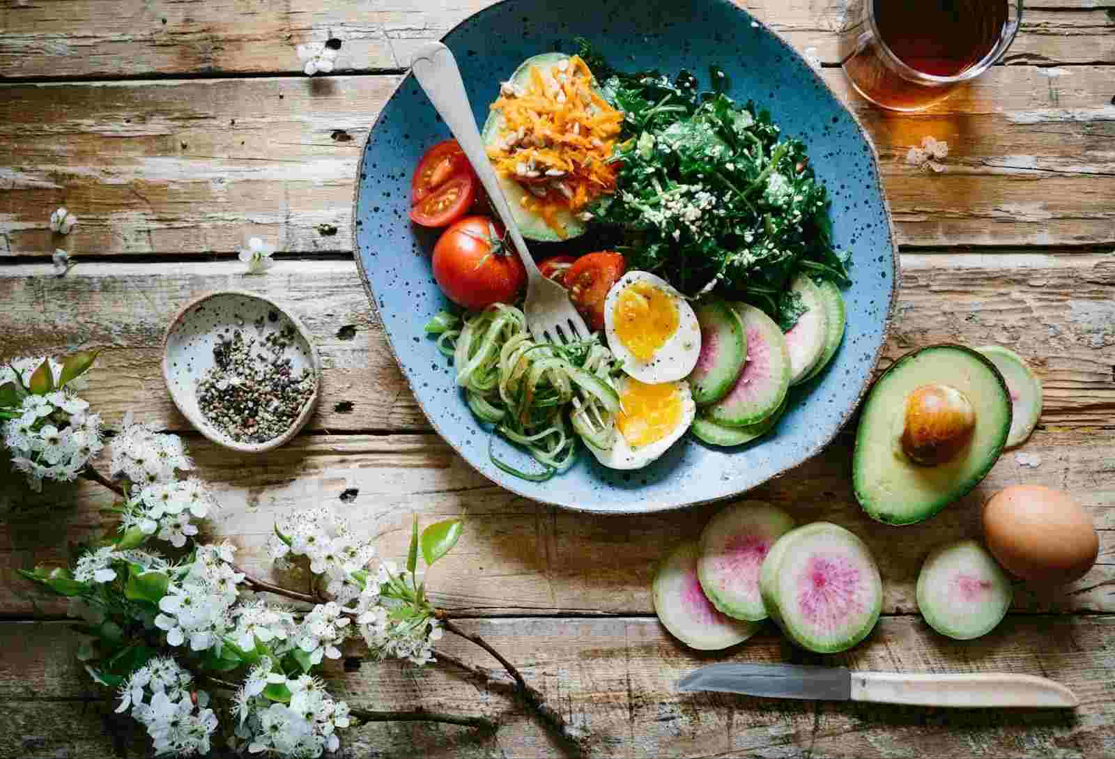 A plate filled with protein-rich food is set on the wooden table alongside a cup of tea