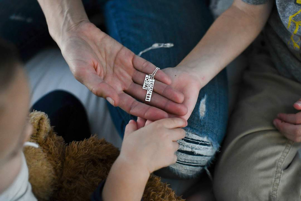 mom’s hand with daughter’s hand, holding a necklace