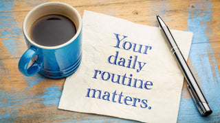 A blue coffee mug next to a silver pen and a napkin with the inscription 