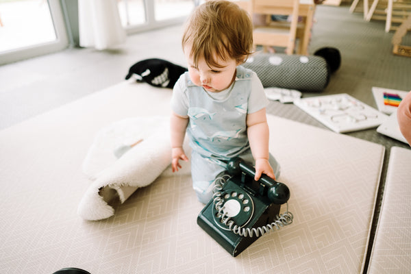 baby in romper with vintage telephone