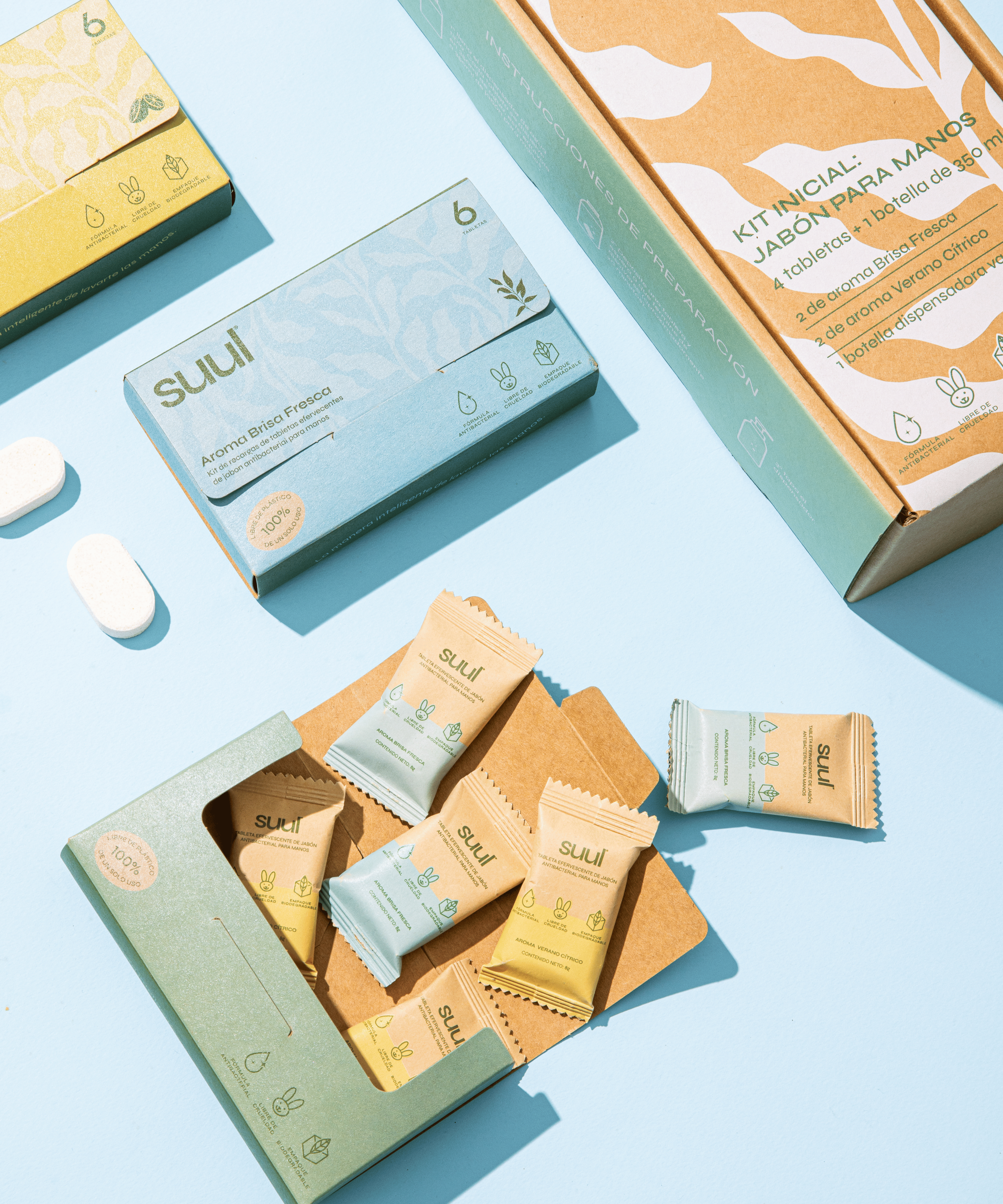 Various wrapped soaps and biodegradable packaging on a light blue background.