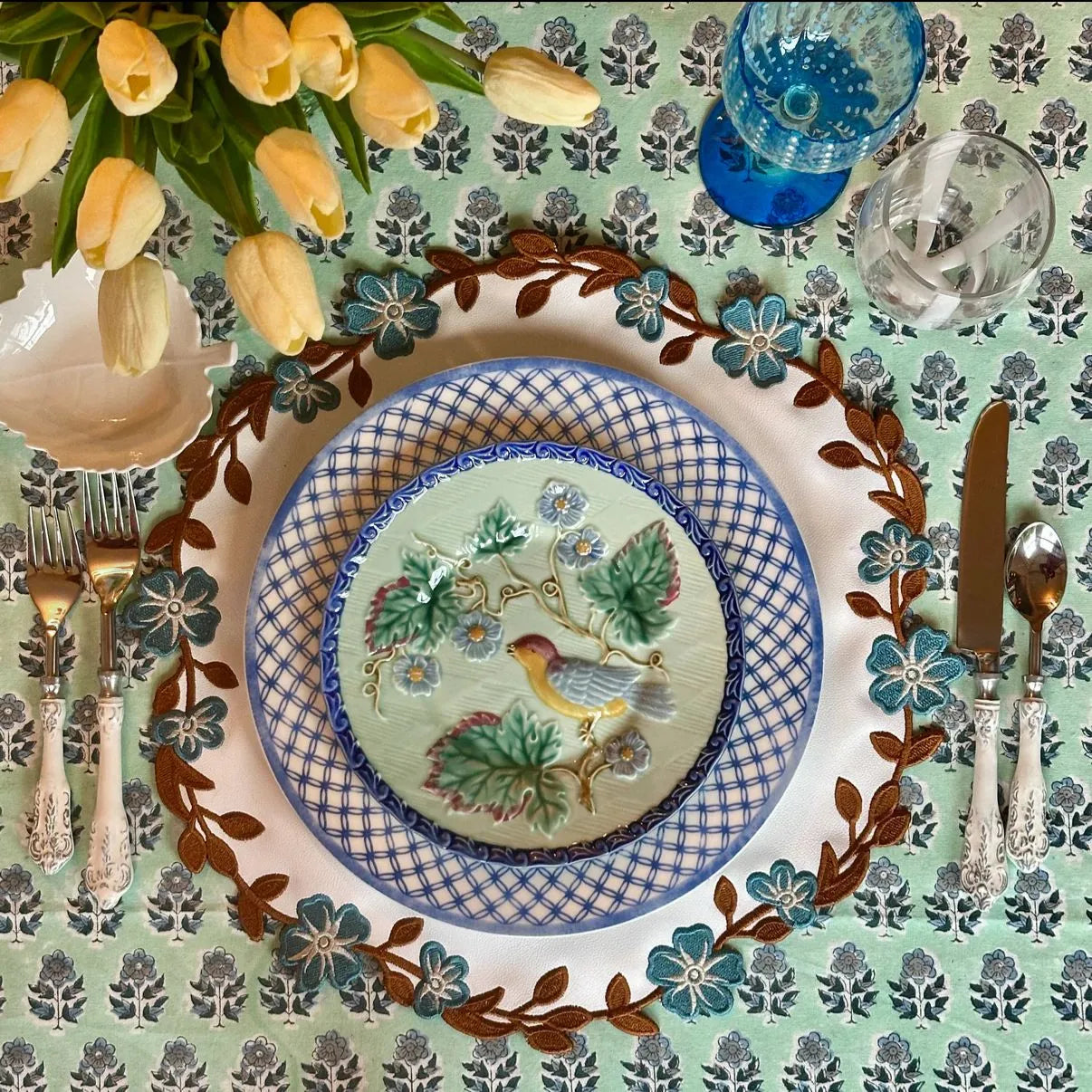 Layered textures flatlay with a wavy faux leather placemat and a Blue Brown fabric placemat with linen napkin and thread spools