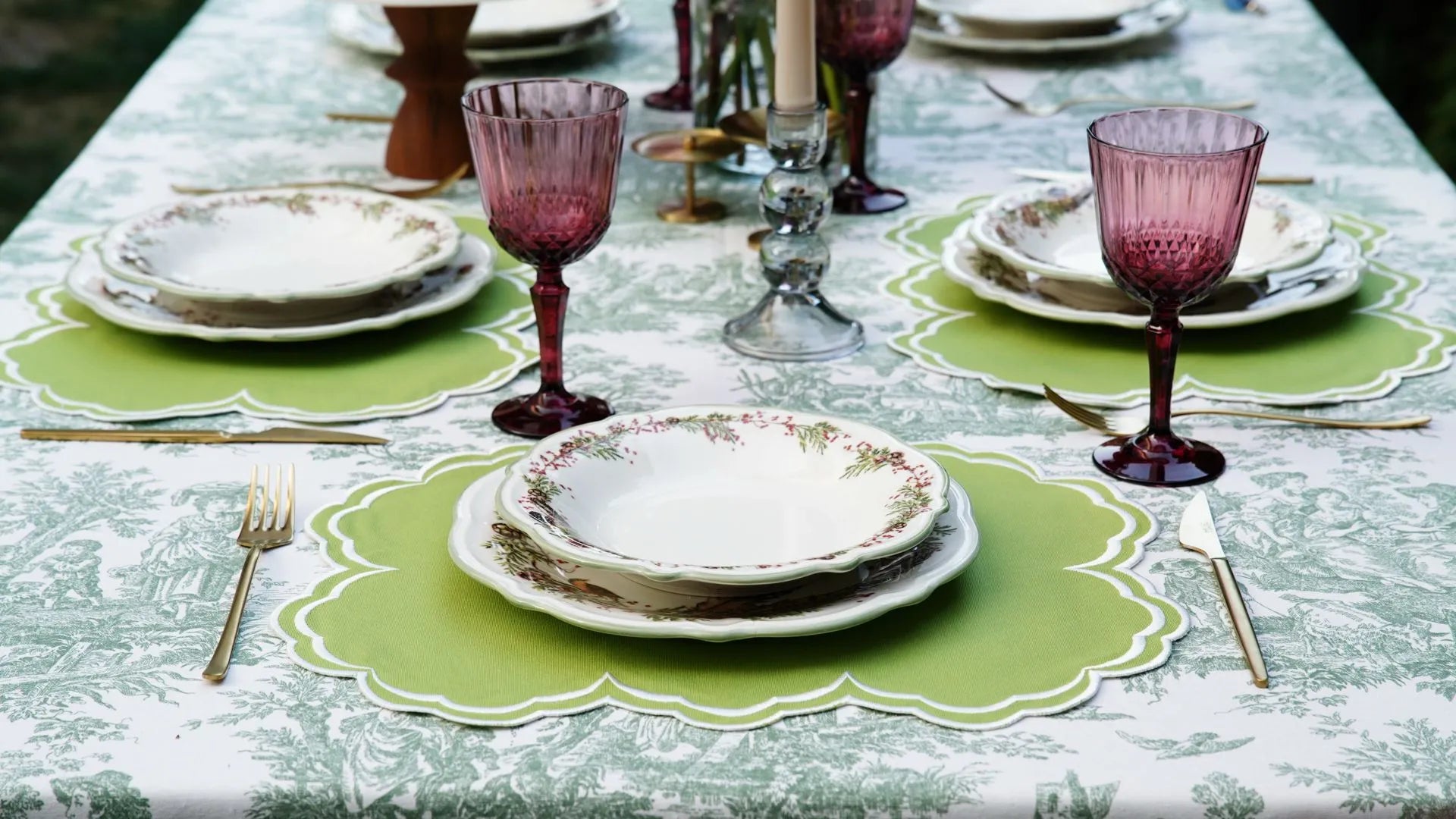 Evenly spaced green embroidered rectangular placemats on a long dining table
