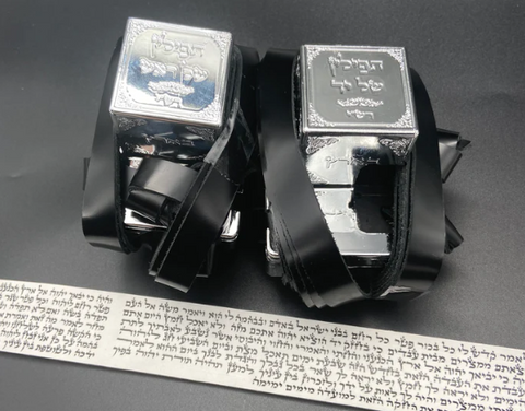 זוג קופסאות עור שחורות המכילות מגילות קלף עבריות