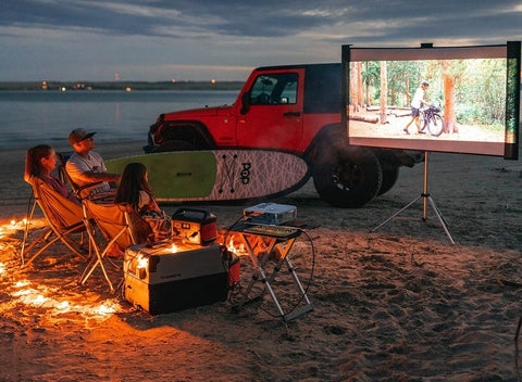 Jackery Portable Power Station On The Beach At Night Powering A Movie Screen