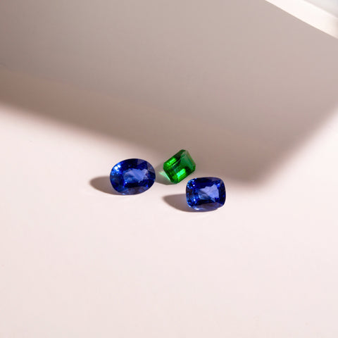 Photo de pierres précieuses posées sur une table; saphir bleu et émeraude verte