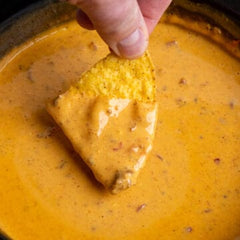 Dipping a tortilla chip in Chili Cheese Dip
