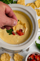 Dipping out Quesco Dip from a Crock Pot with a tortilla Chip