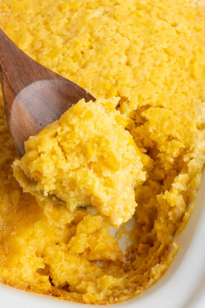 Crock Pot Corn Casserole being served with a wooden spoon